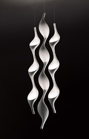 A tall white sculpture of wavy lines on black background.