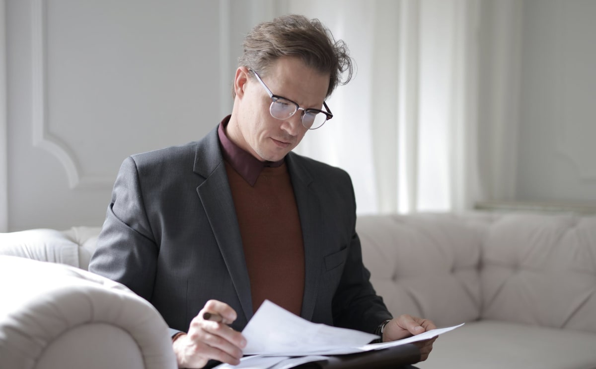 A man in glasses is looking at papers.