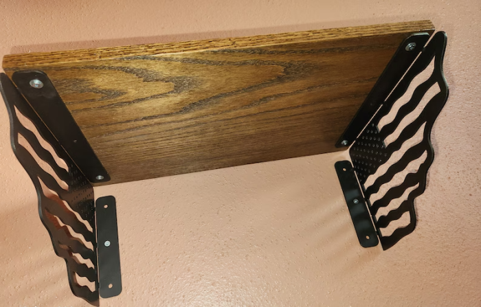 A wooden table with black metal legs and two black brackets.