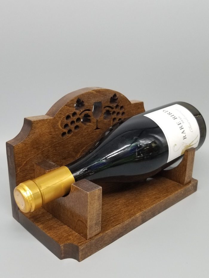 A wooden wine holder with a bottle of wine on top.