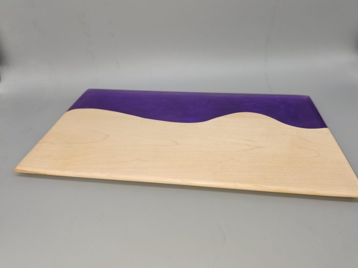 A wooden board with purple and white waves on it.