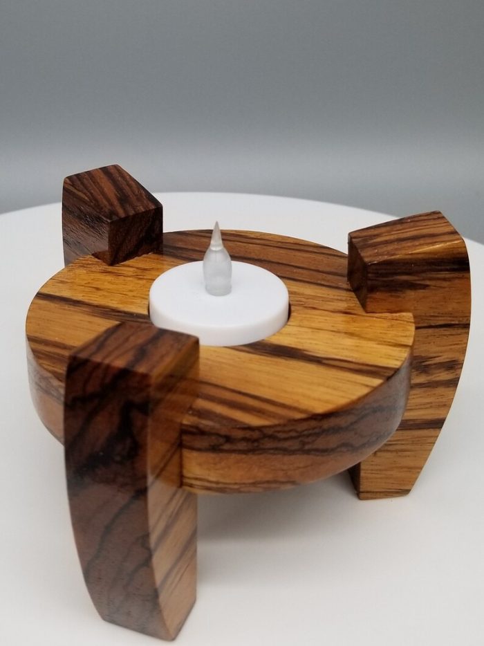 A candle holder made of wood with a white candle.