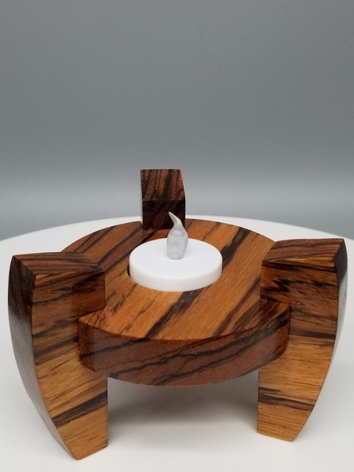 A candle holder made of wood with a white candle.