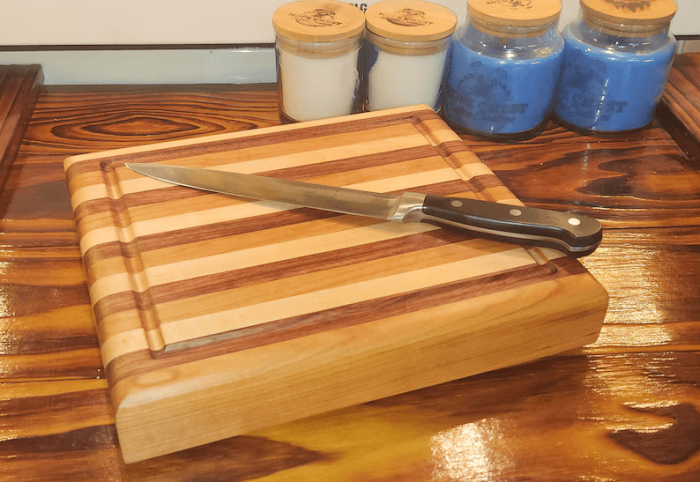 A cutting board with a knife and some jars