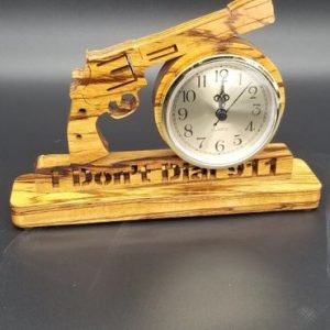 A wooden clock with a gun on top of it