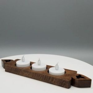 A wooden candle holder with three candles on top of it.