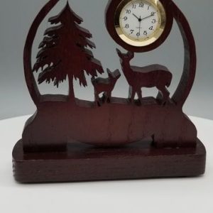 A wooden clock with deer and trees on it.