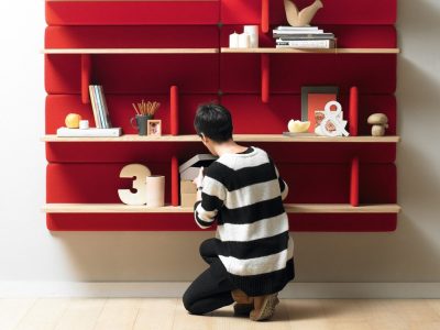 A person kneeling down in front of shelves.